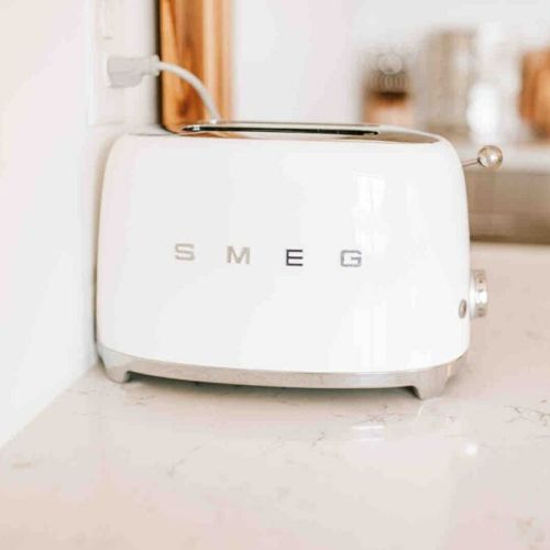 Add a pop of style to your morning routine: this kitchen comes equipped with a sleek Smeg toaster, combining vintage design with modern functionality.