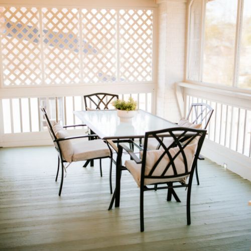 Relax and unwind: this porch is furnished with comfortable chairs, inviting you to sit back, relax, and enjoy.