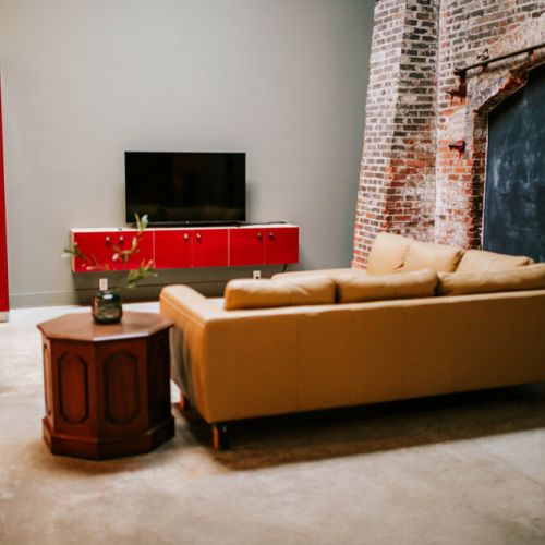 The open concept living area features a unique floor to ceiling brick wall that is from the original construction of the warehouses.