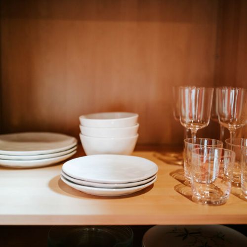 There are plates, glasses, dishes, and mugs for four guests.
