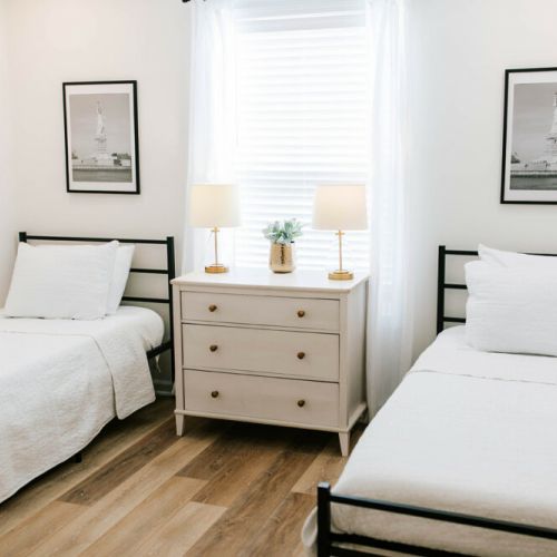 This bedroom features two, comfortable single beds, nightstands, and lamps for each person.