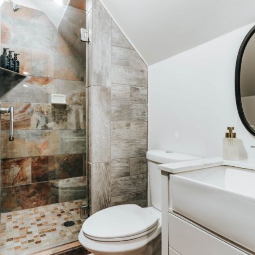 Refresh in this stylish bathroom featuring a beautifully tiled walk-in shower with glass enclosure, a sleek vanity, and a statement round mirror. Thoughtful finishes create a polished, comfortable space for getting ready or winding down.