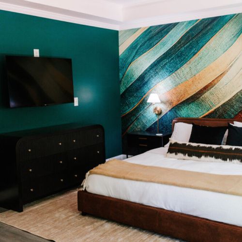 Sleep in style beneath bold art and emerald walls, with treetop views and designer flair that make this room a showstopper!