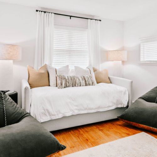 Cozy room with a daybed, soft lighting, and bean bag chairs — perfect for lounging or extra sleeping space.