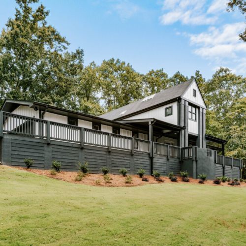 Spacious home with a large wraparound deck and peaceful wooded surroundings.