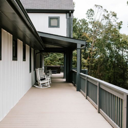 Spacious porch with rocking chairs, perfect for relaxing and enjoying the wooded views.