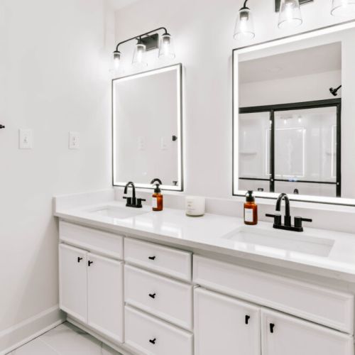 Crisp design meets everyday luxury—double sinks, glowing mirrors, and plenty of space to refresh.