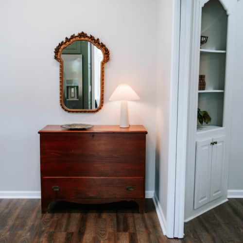 A cozy corner with vintage charm ✨ This welcoming nook—complete with an antique chest, soft lighting, and a golden mirror—adds warmth and character to your stay from the moment you walk in.