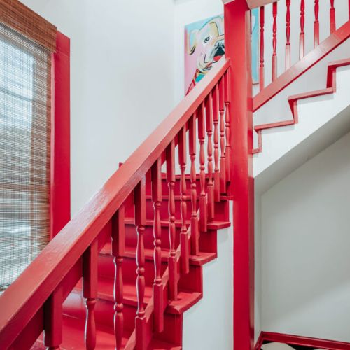 Make your way upstairs along the bold red staircase, where vibrant artwork and natural light add personality at every turn. This colorful architectural detail brings a playful, one-of-a-kind character to your stay.