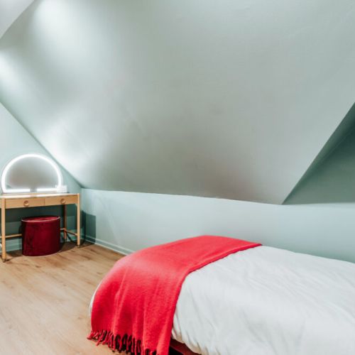 Tucked beneath charming sloped ceilings, this private sleeping nook offers crisp linens and a warm pop of color. Settle in for a peaceful night, then enjoy a quiet corner to get ready and ease into the morning.