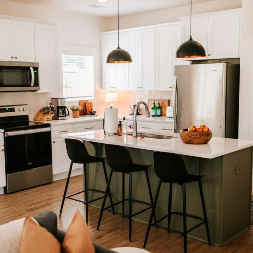 Modern elegance meets functionality: This luxurious kitchen features stainless steel appliances and an island with seating for three, ideal for entertaining guests while preparing gourmet meals.