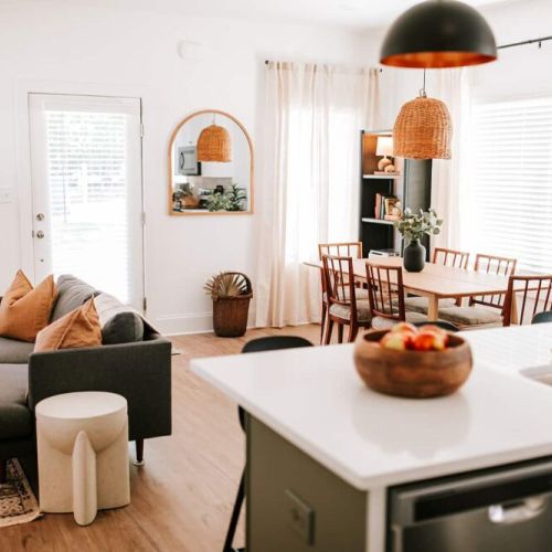 The kitchen opens up to the contemporary dining area, which features a large wooden table with seating for six.