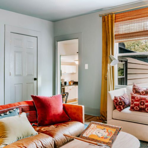Settle into this vibrant living room filled with natural light, cozy seating, and bold artistic touches. It’s an inviting spot to sip your morning coffee, share conversation, or relax together after a day of exploring.