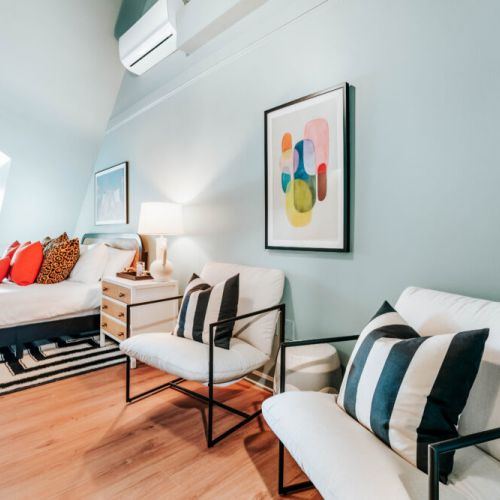 Unwind in a stylish bedroom designed for more than sleep, with crisp linens, comfortable lounge chairs, bold artwork, and in-room A/C. Enjoy a quiet morning by the window or settle in and recharge after a full day of exploring.