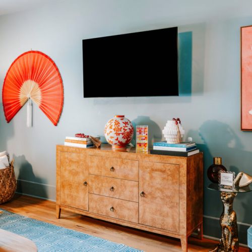 Settle in for movie night with a wall-mounted TV and a living room full of personality. Bold artwork, curated décor, warm wood accents, and comfortable seating create a memorable space to relax, stream your favorites, and enjoy time together.