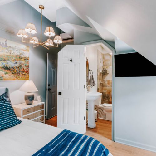 Settle into this stylish bedroom with crisp linens, soft bedside lighting, a wall-mounted TV, and a private bathroom just steps from the bed. Thoughtful details and unique architecture create an inviting retreat for relaxing and recharging.