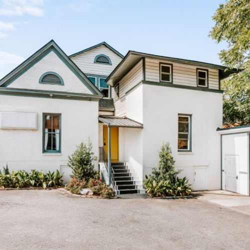 Arrive at your inviting home away from home, where a cheerful yellow door welcomes you inside. Surrounded by greenery and distinctive architecture, this charming retreat sets the stage for a relaxing and memorable stay.