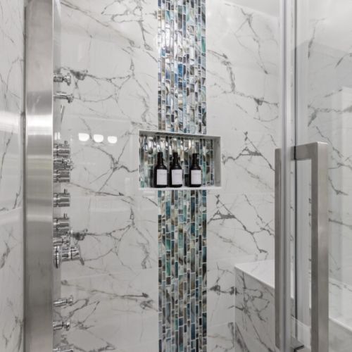Indulge in a rejuvenating rain shower surrounded by sleek marble and shimmering mosaic tiles—your personal spa escape awaits!