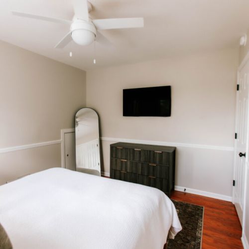 Wake up slow in this bright, airy bedroom—complete with a wall-mounted TV, full-length mirror, and sleek modern dresser to make you feel right at home.