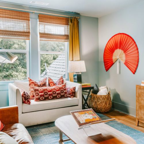 Settle in for a relaxing evening in this light-filled living room, complete with comfortable seating, a wall-mounted TV, curated décor, and leafy views. It’s an inviting space for movie nights, conversation, or a quiet moment with a book.